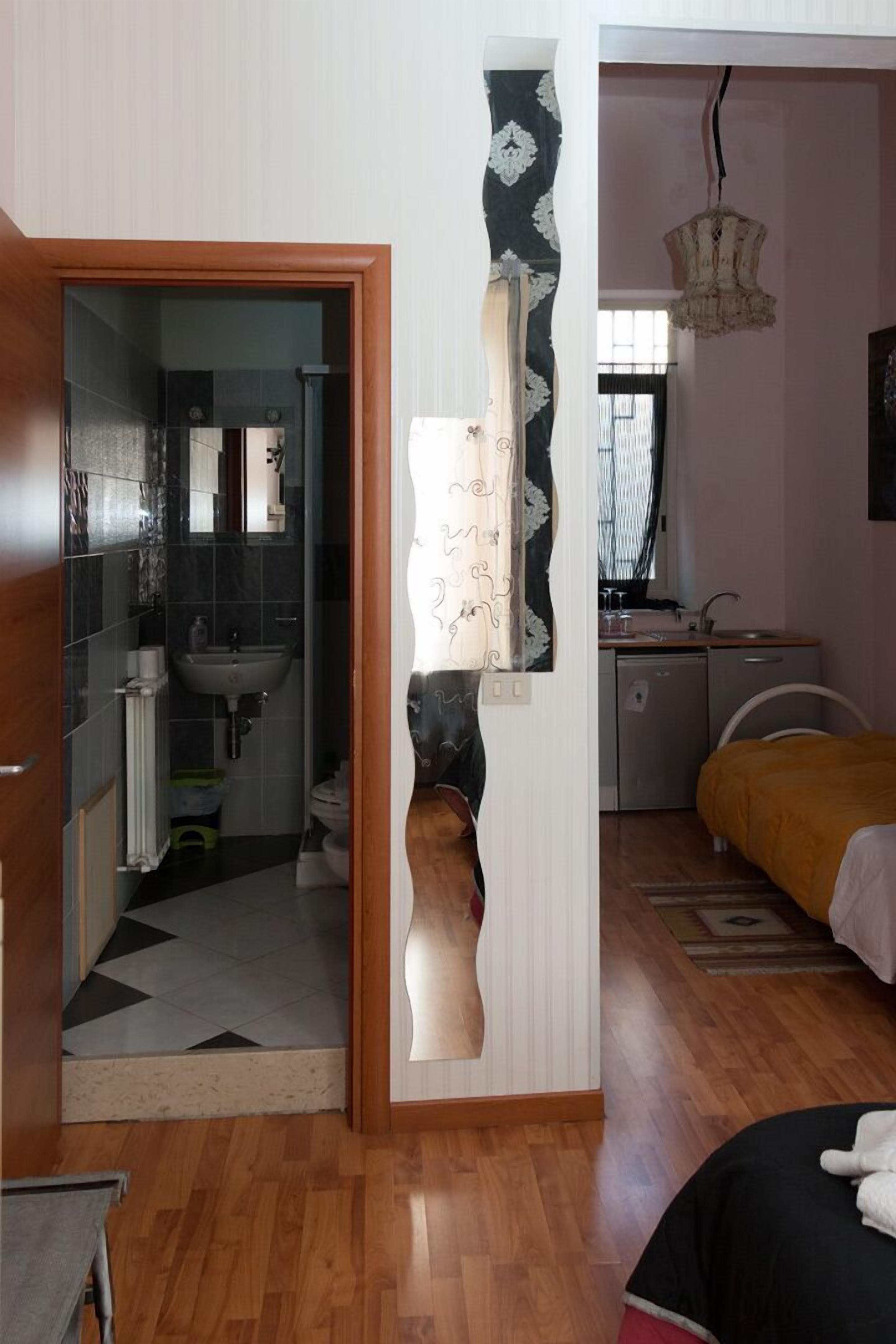 A bedroom with a bed, a bedside table, a dresser, and a window.