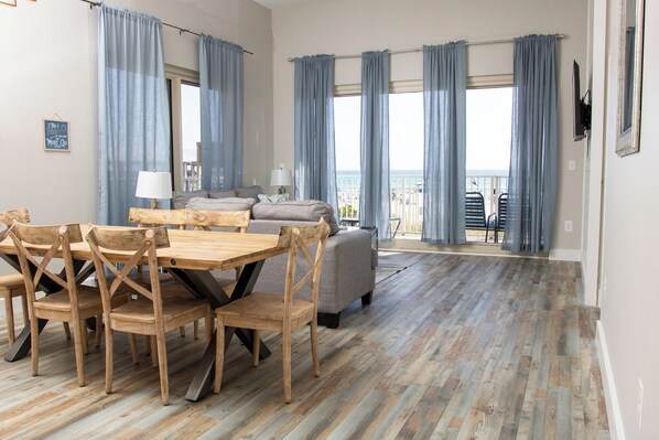 Amplia sala de estar con una mesa y sillas de madera, un sofá y un balcón con vistas.