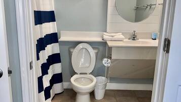 Un baño con inodoro, lavamanos y cortina de ducha.