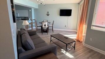 A modern living room with a sofa, coffee table, and dining area.