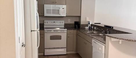 A compact kitchen with a refrigerator, microwave, stove, and dishwasher.