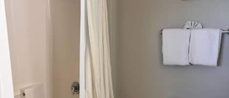 A bathroom with a shower, toilet, and a towel rack.