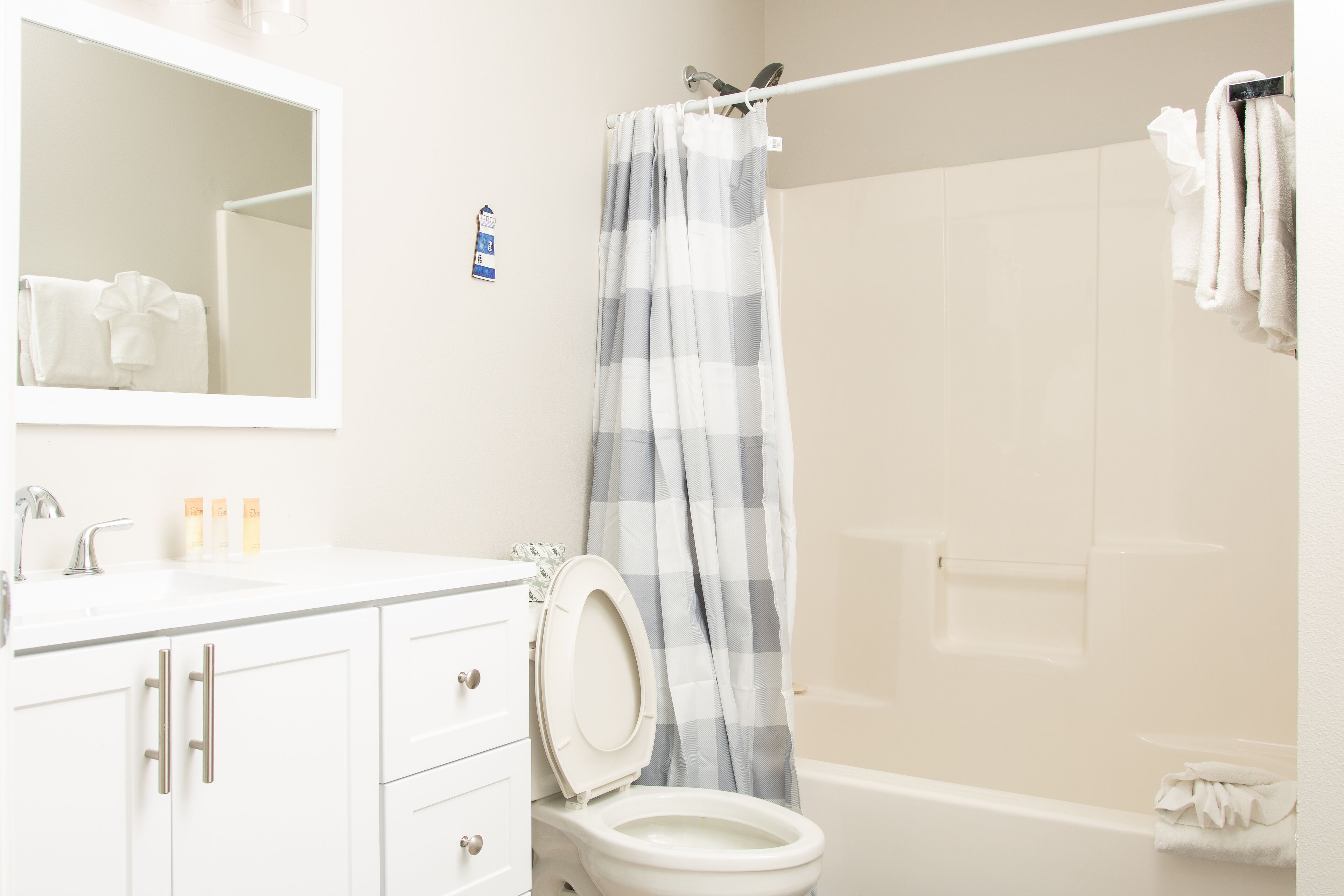 A bathroom with a white sink, a mirror, a toilet, and a shower curtain.