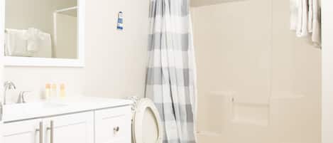A bathroom with a white sink, a mirror, a toilet, and a shower curtain.