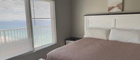 A bedroom with a bed, a nightstand, and a window with blinds.