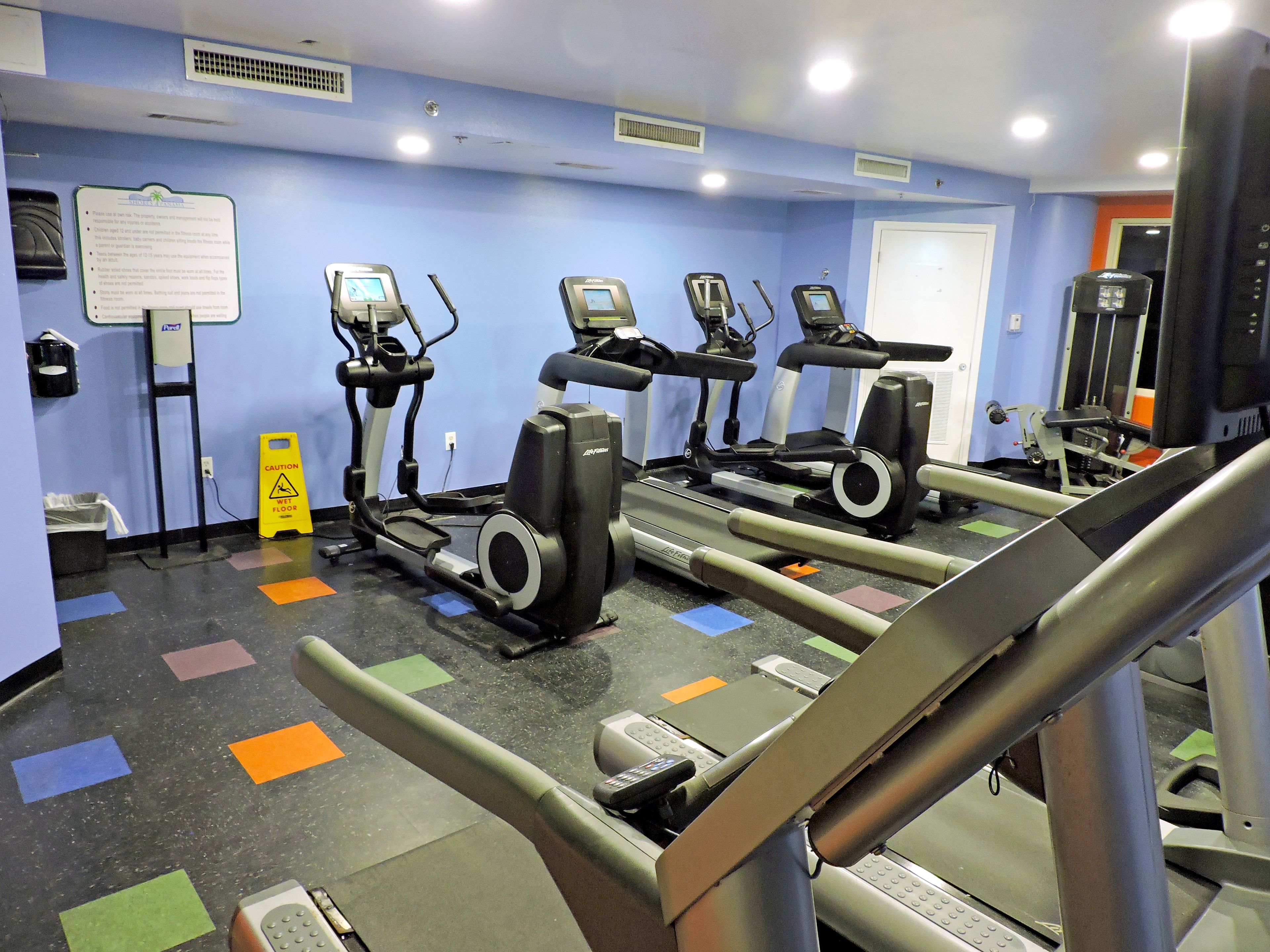 A gym with treadmills, elliptical machines, and a weight bench.