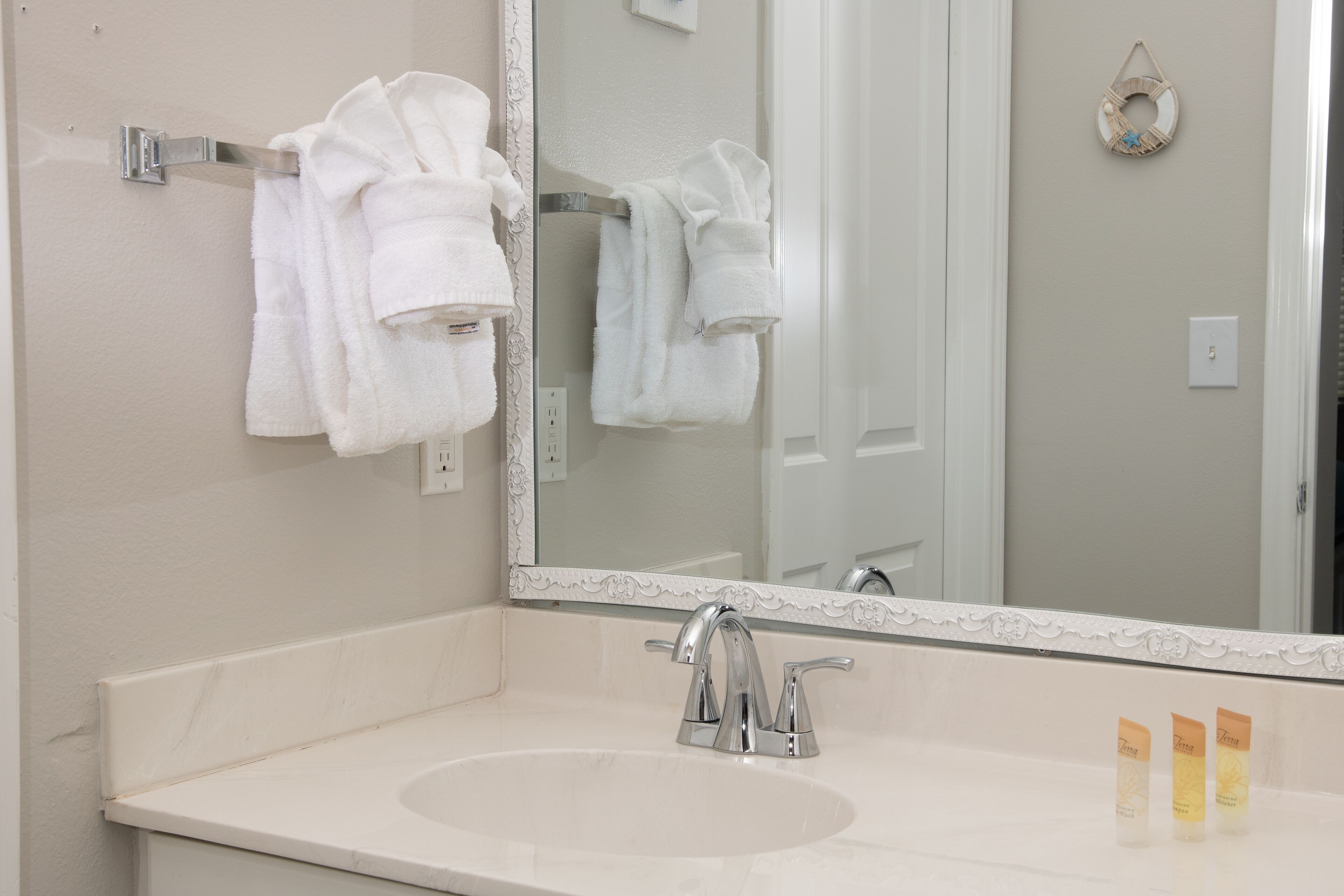 A bathroom with a white sink, two faucets, and a mirror with a decorative frame.