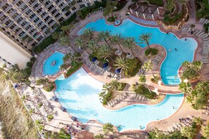 A large, multi-level swimming pool with palm trees and sun loungers, surrounded by a hotel building. - Shores of Panama Beach Resort (Panama City Beach)