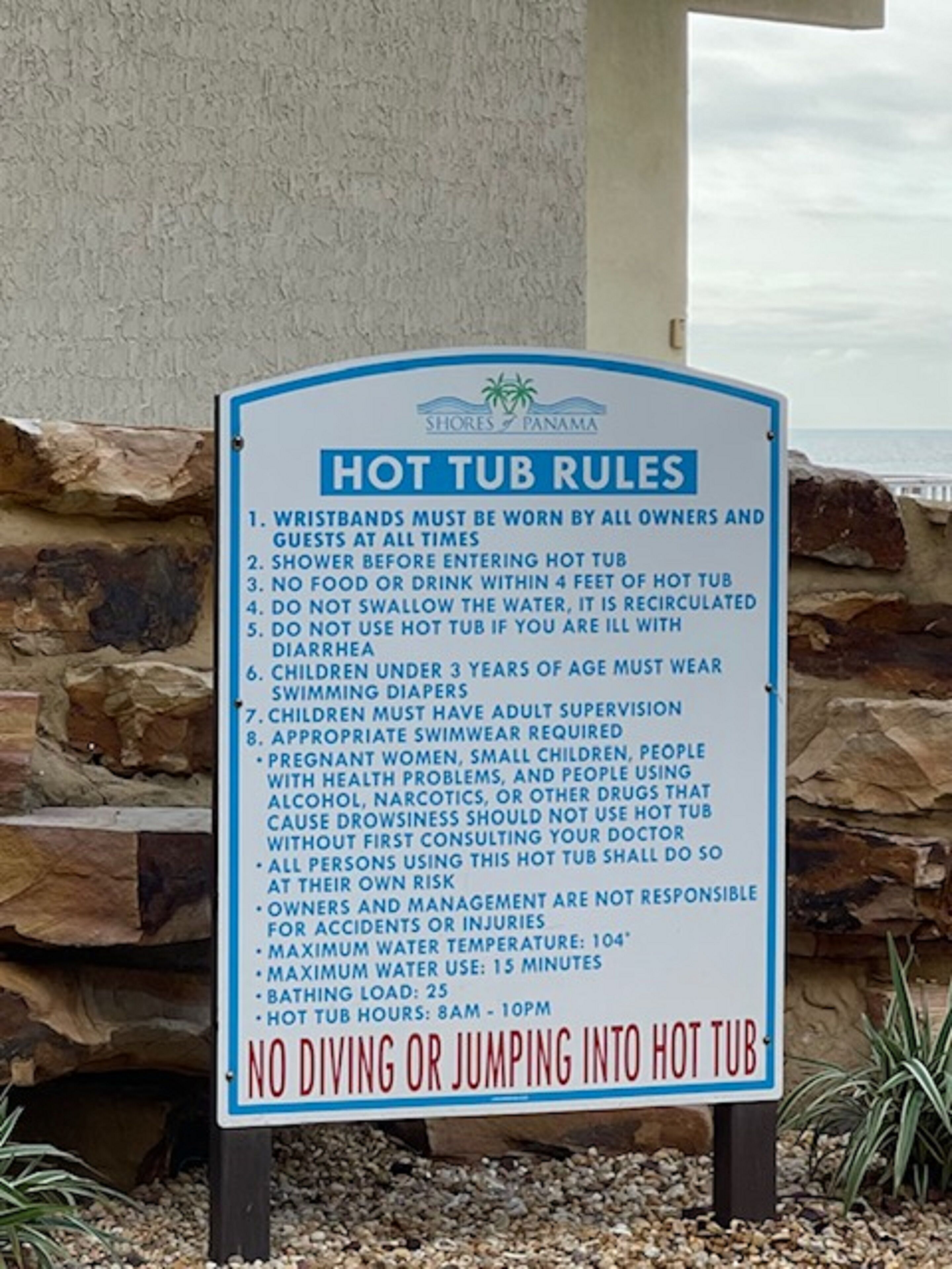A sign listing hot tub rules including wristband requirements, supervision for children, and no diving or jumping.
