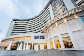 Experience the unique architecture of this hotel, featuring a curved facade with multiple levels of balconies and large windows.