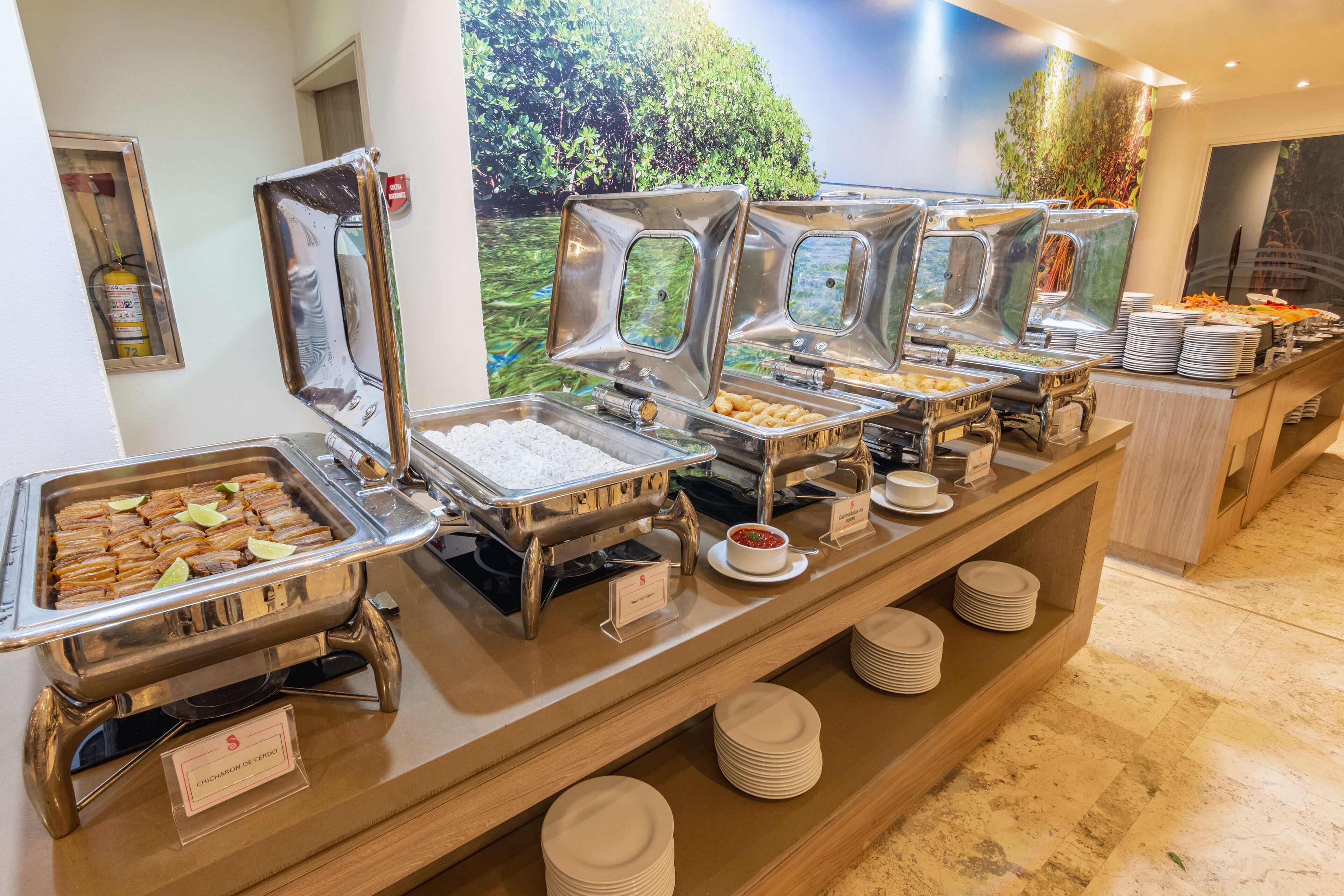 A buffet setup with various food stations, including a fruit display and a hot food station.