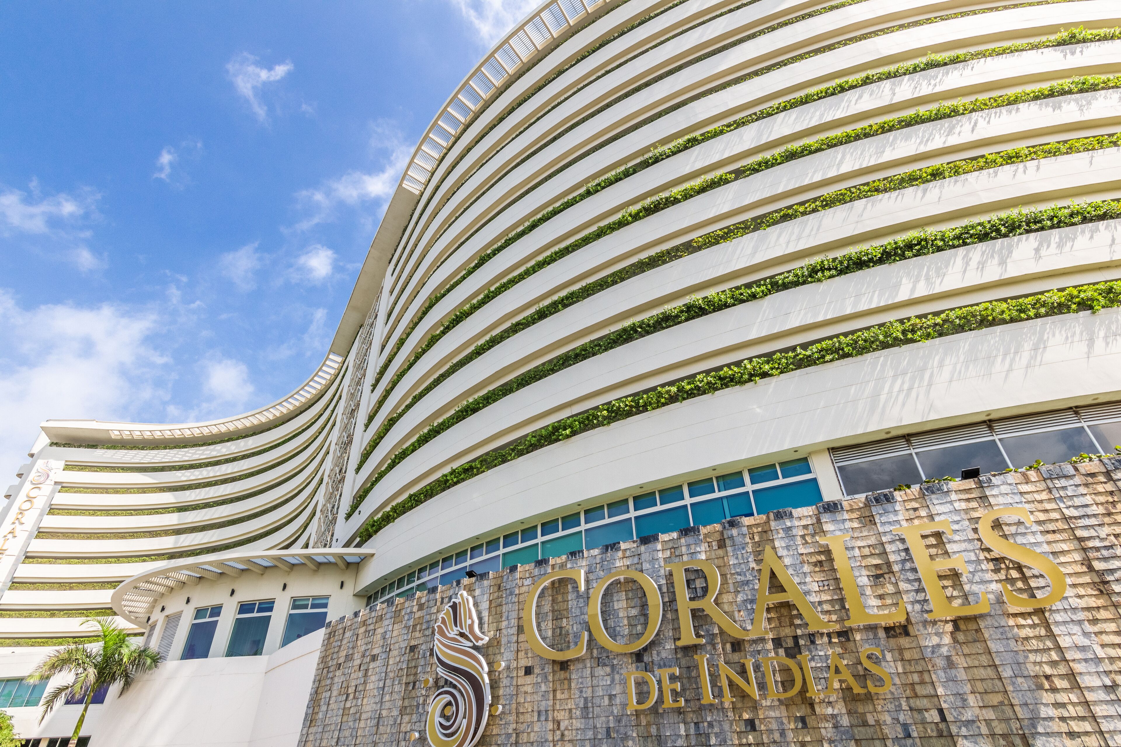 A modern building with a curved facade and a sign that reads "CORALES DE INDIAS".