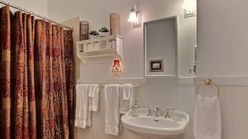 Un baño con un lavamanos blanco, dos toalleros, un espejo y una cortina de ducha.