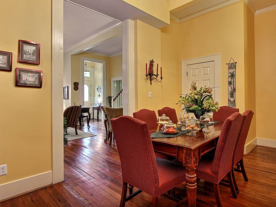 A dining area with a wooden table, red patterned chairs, and a chandelier.