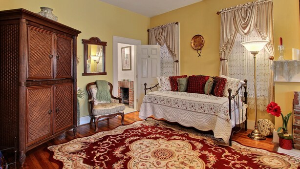 Una habitación con una cama, un armario de madera, una silla, una lámpara y una alfombra.