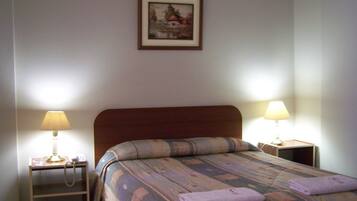 A neatly made bed with a patterned bedspread and two bedside lamps.