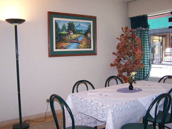 A dining area with a table set for six, a framed painting on the wall, and a potted plant. - Imperium Hotel Lima (Lima)