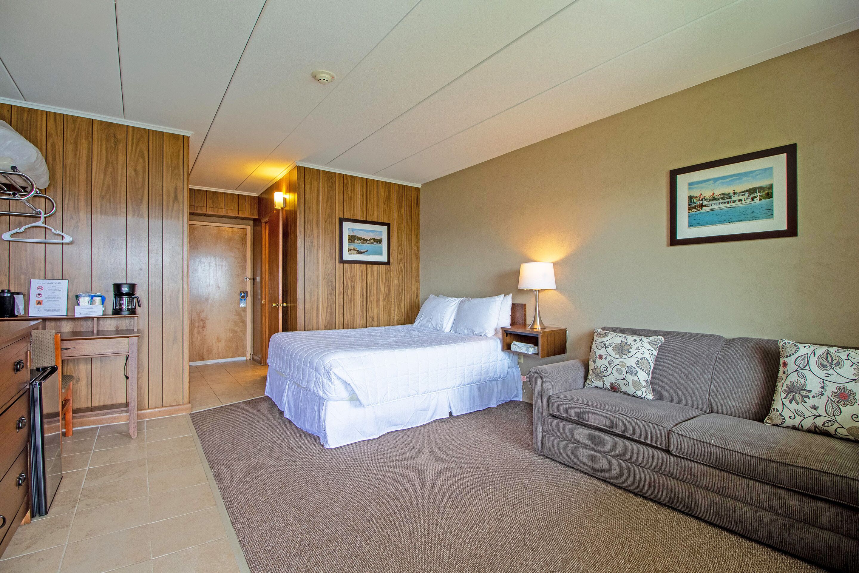 Een hotelkamer met een bed, een bank, een bureau en een ingelijst schilderij aan de muur.