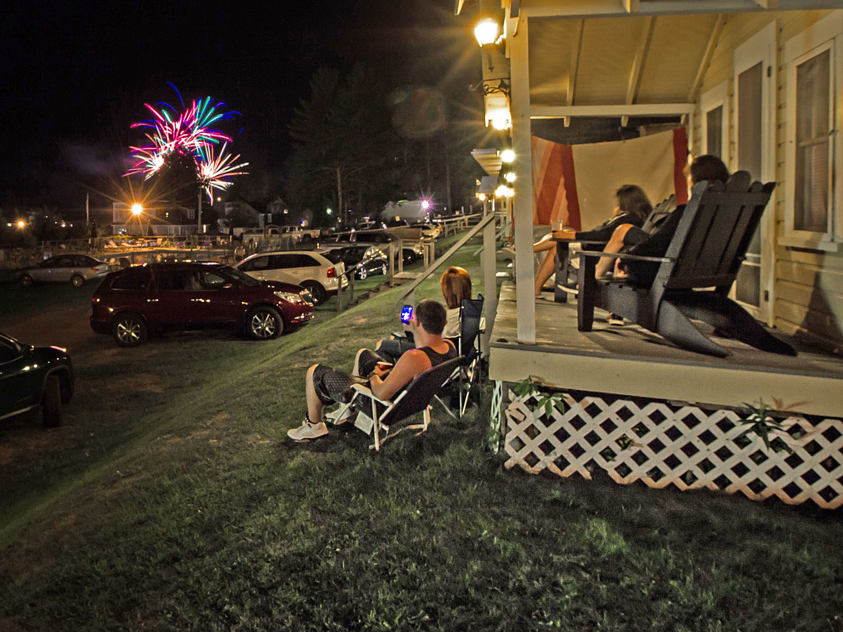 A porch with outdoor seating, a lawn, and parked cars.