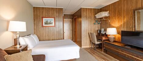 Une chambre d’hôtel comprenant un lit, un bureau avec une chaise, une télévision et un porte-manteau.