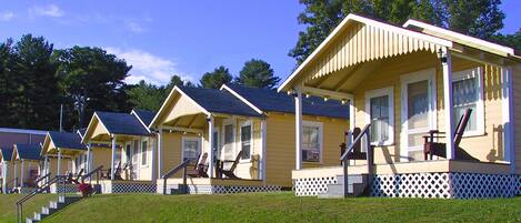 A row of small, single-story cabins with a porch and steps leading to the entrance.