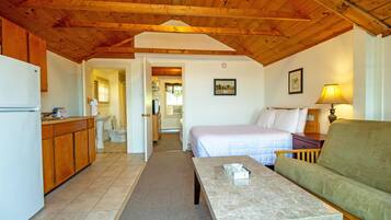A cozy room with a bed, a sofa, a table, and a kitchen area.