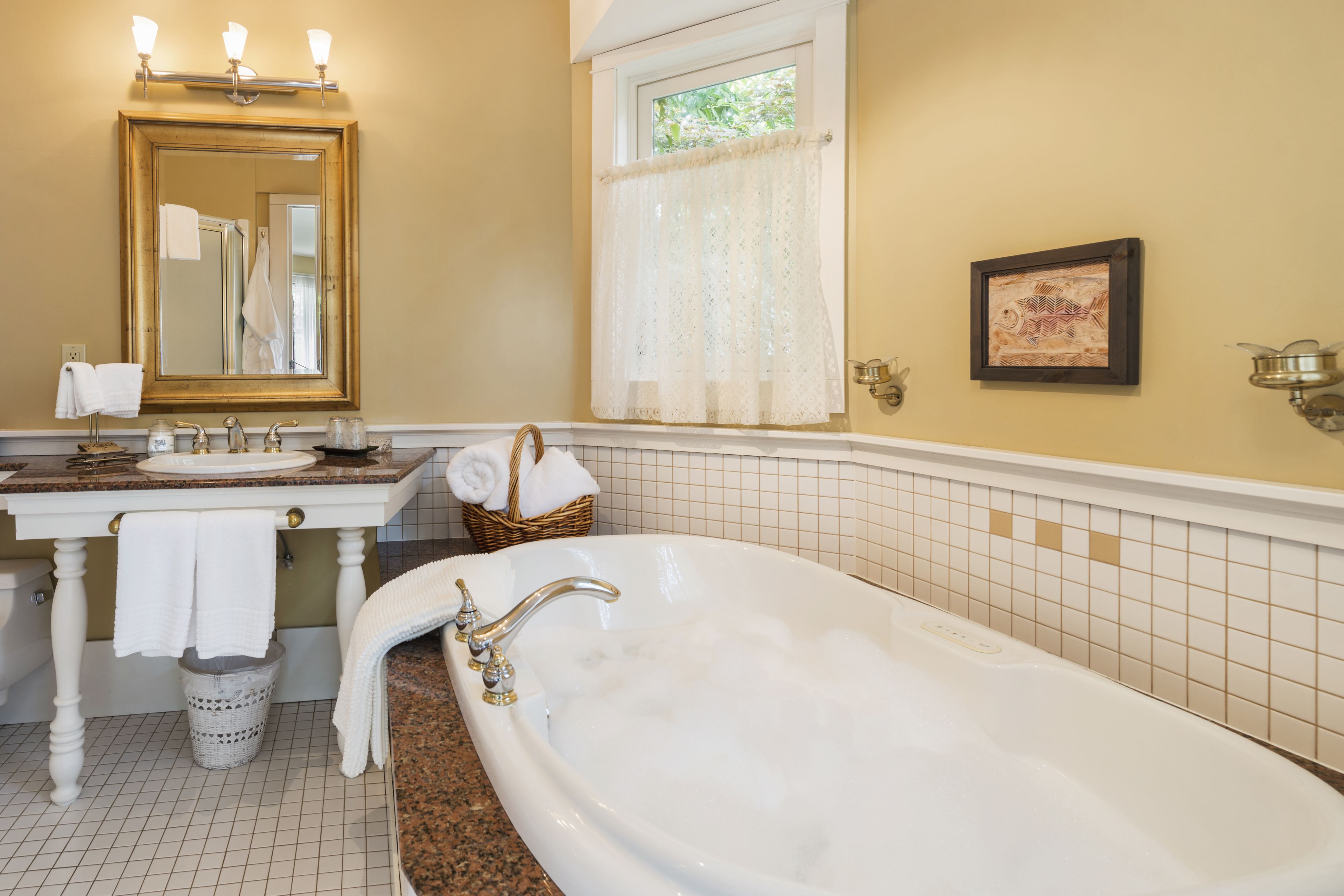 A bathroom with a bathtub, two sinks, a large mirror, and a window with a curtain.