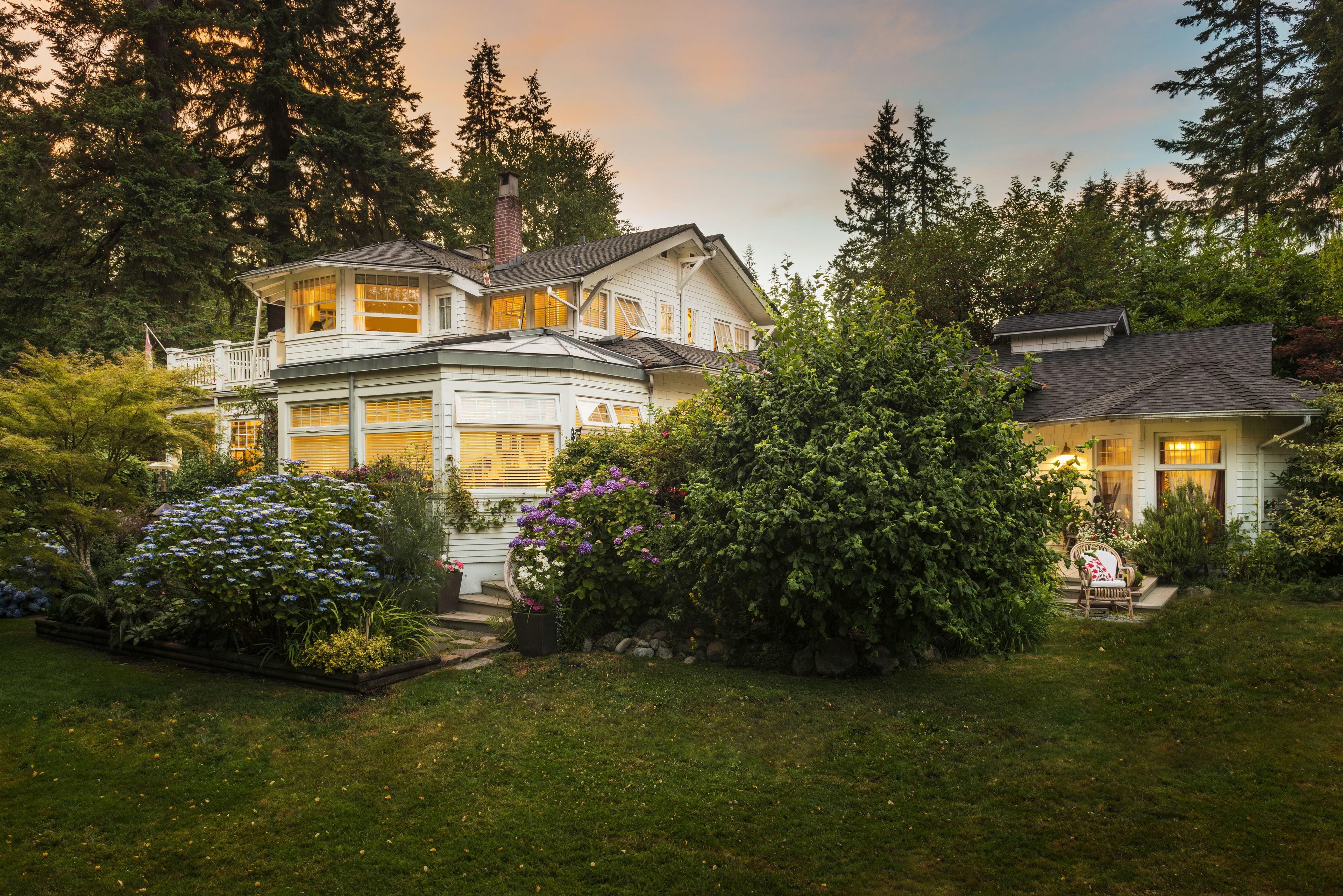 A two-story house with a large garage, surrounded by lush greenery and trees.
