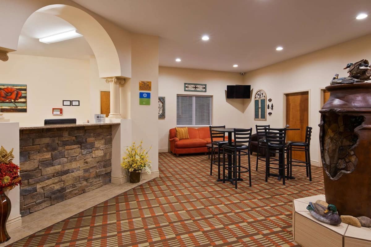 A reception area with a stone fireplace, a reception desk, a sofa, and a dining area with chairs.