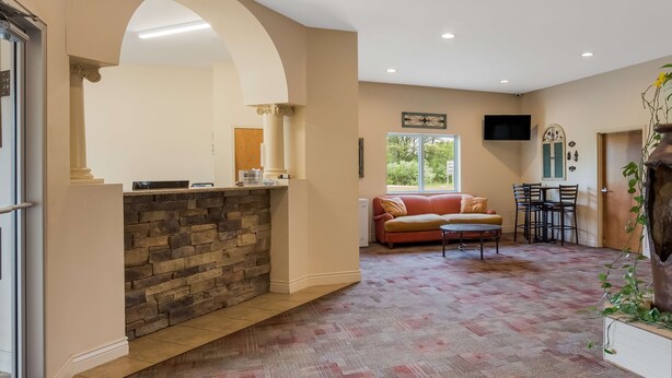 A spacious lobby with a stone fireplace, a seating area with a sofa and chairs, and a television mounted on the wall.