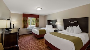 A hotel room with two beds, a desk, a chair, a TV, and a window with curtains.