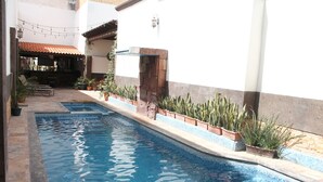 A swimming pool with a stone wall and potted plants. - Hotel Rincón Real Suites (Durango)