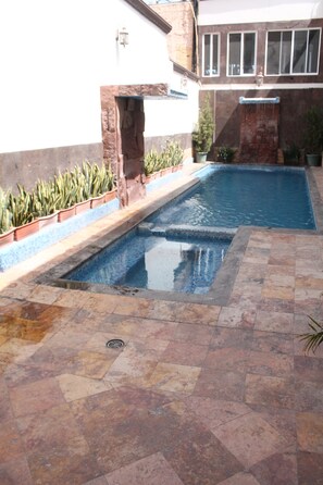 Piscina com borda de pedra e pequena cascata.