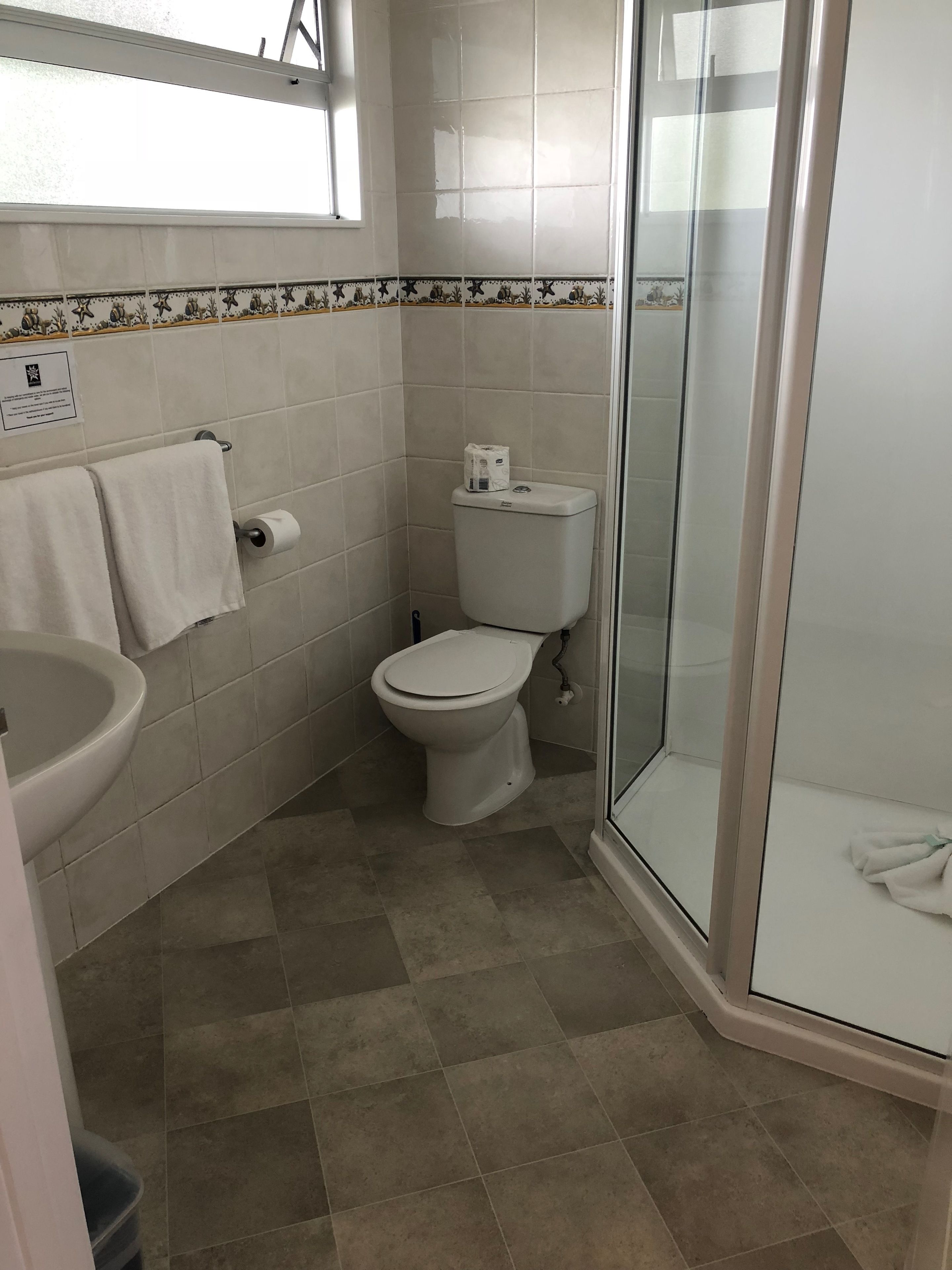A bathroom with a toilet, sink, and glass shower enclosure.