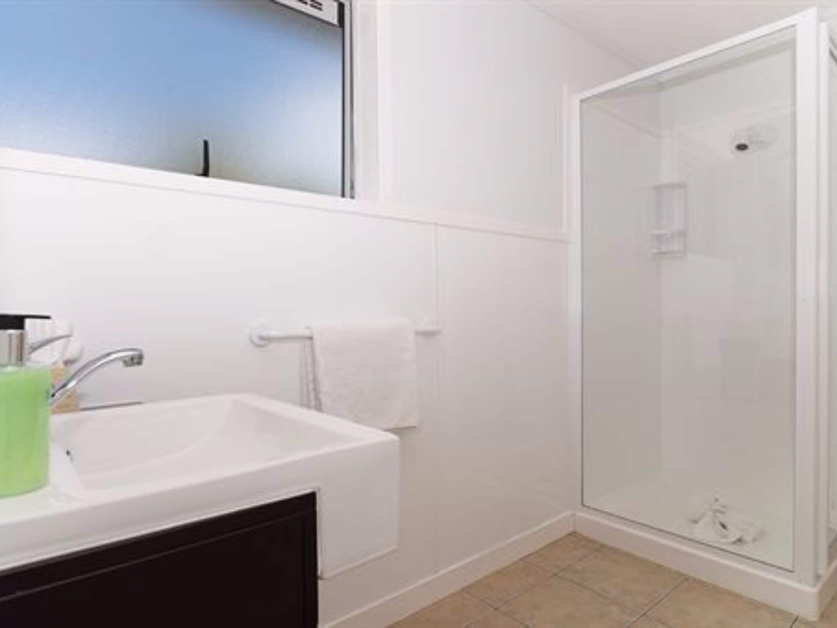 A bathroom with a white sink, a glass shower enclosure, and a mirror above the sink.