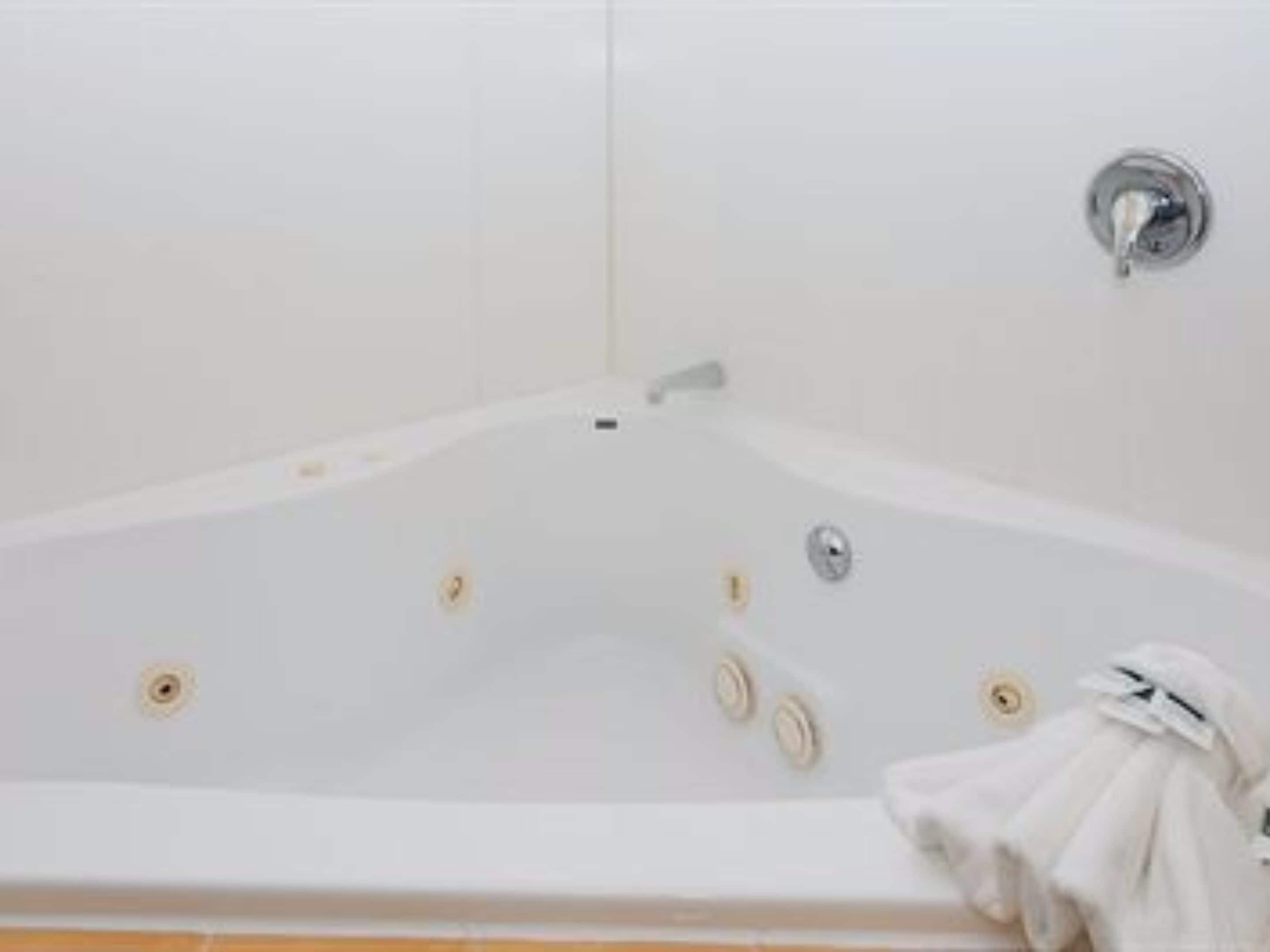A white bathtub with a showerhead and a towel hanging on the side.