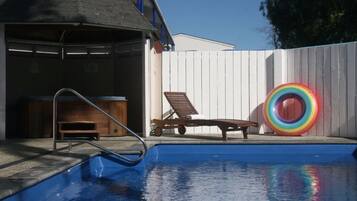 Una piscina al aire libre, sillones reclinables de piscina