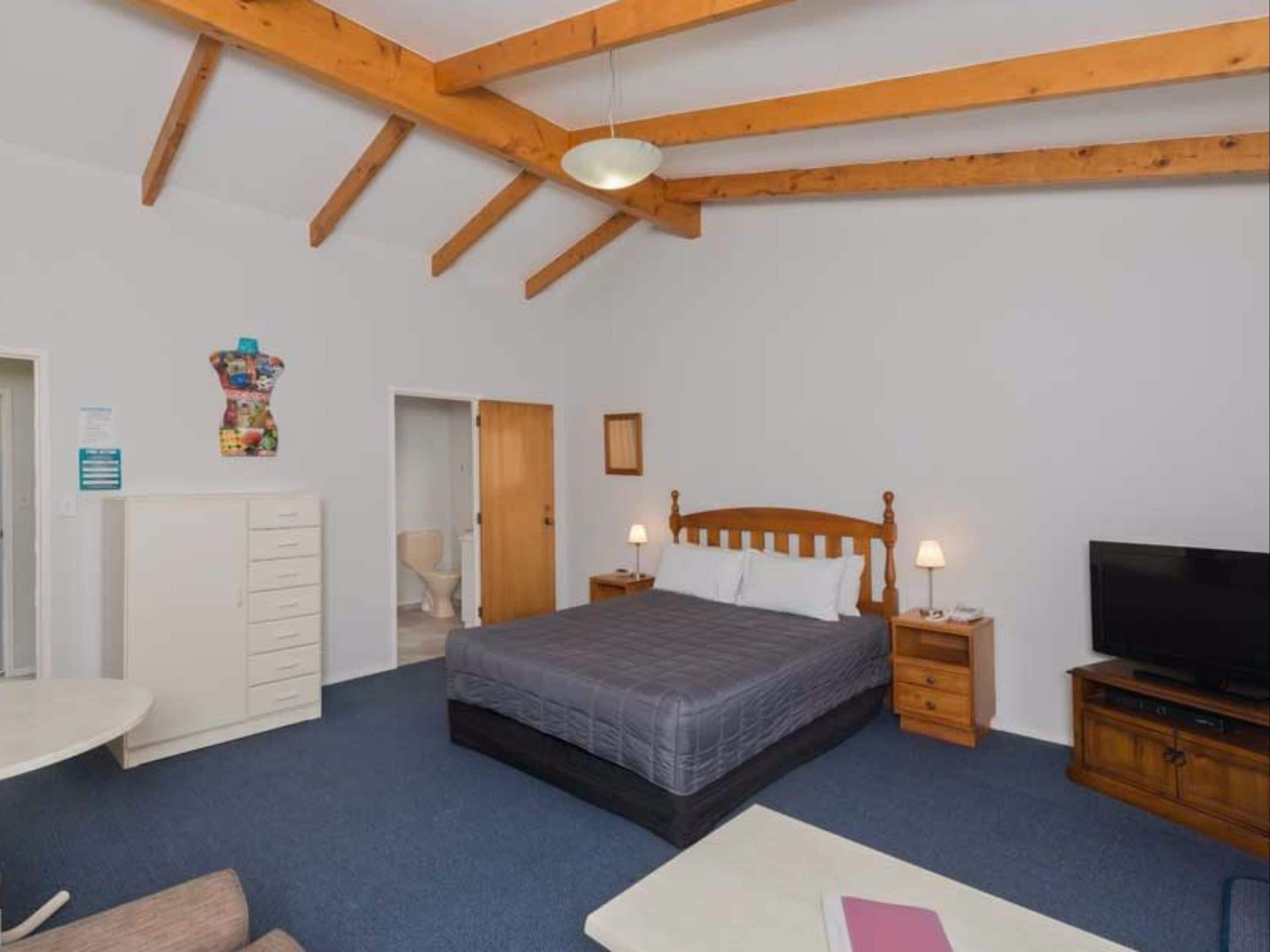 A bedroom with a bed, bedside tables, a TV, a desk, and a wardrobe.