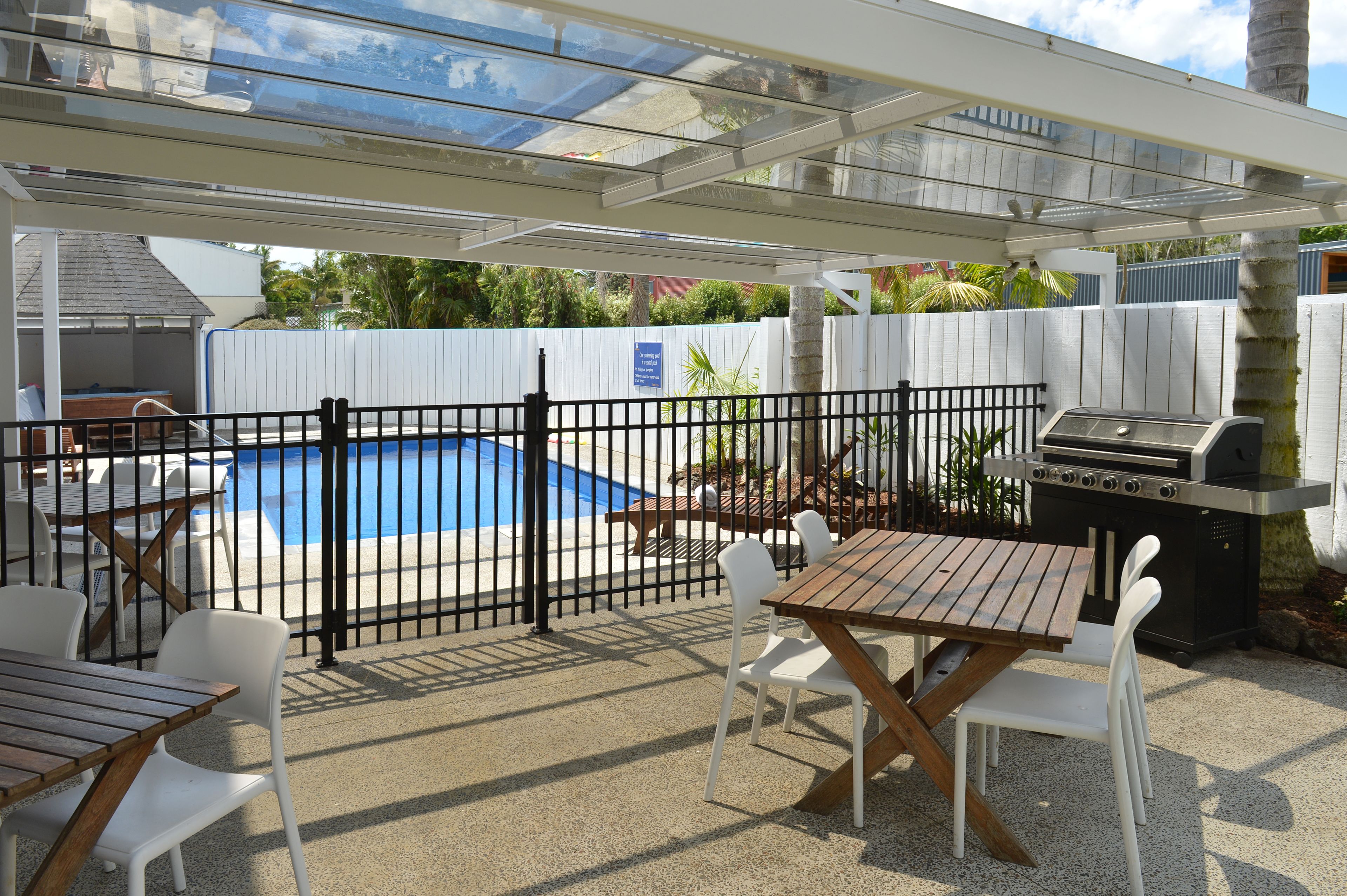 An outdoor patio area with a pool, a grill, and seating arrangements.