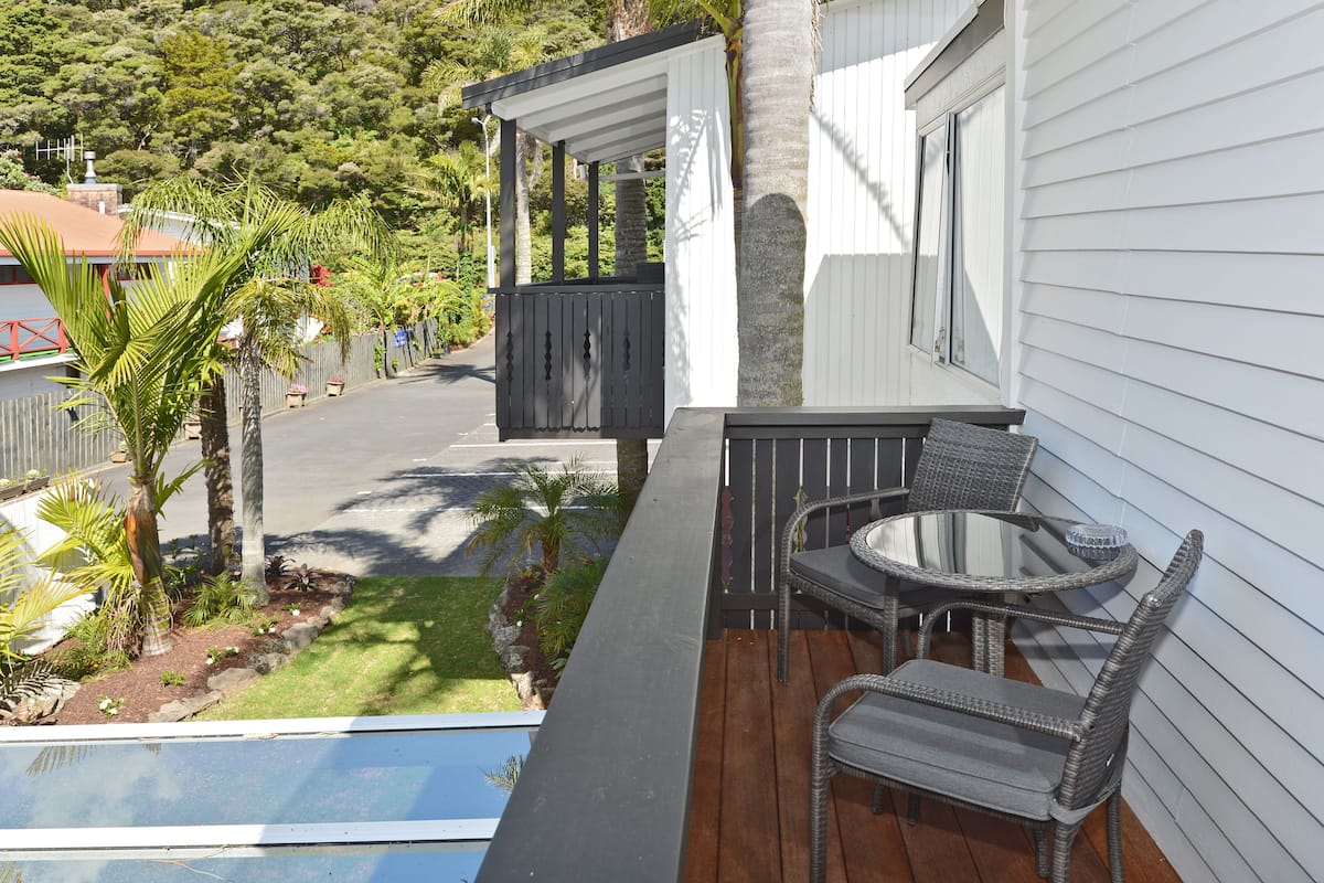 A deck with wicker furniture, a small pool, and a view of a street and greenery.