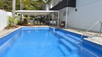 Una piscina al aire libre, sillones reclinables de piscina