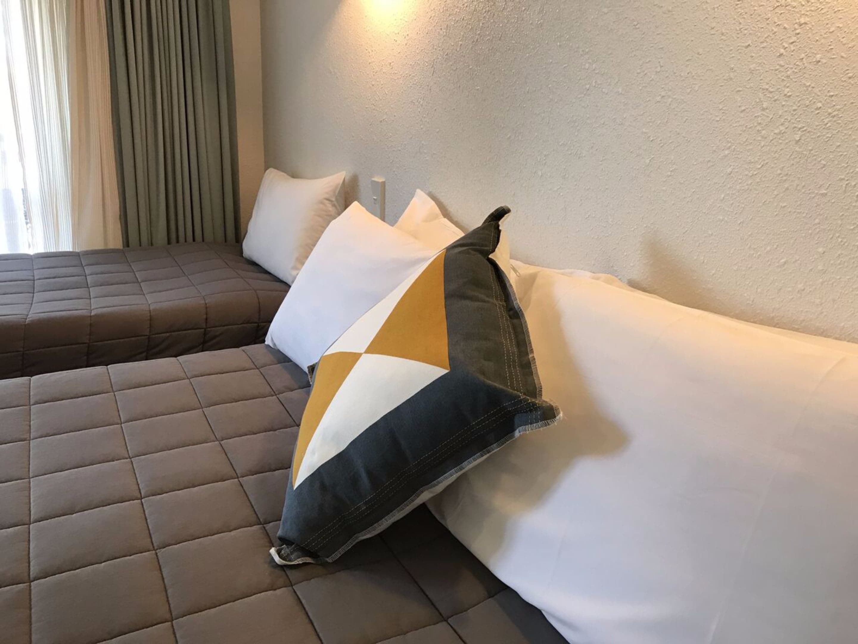 A modern hotel room with a sectional sofa and a large window with curtains.