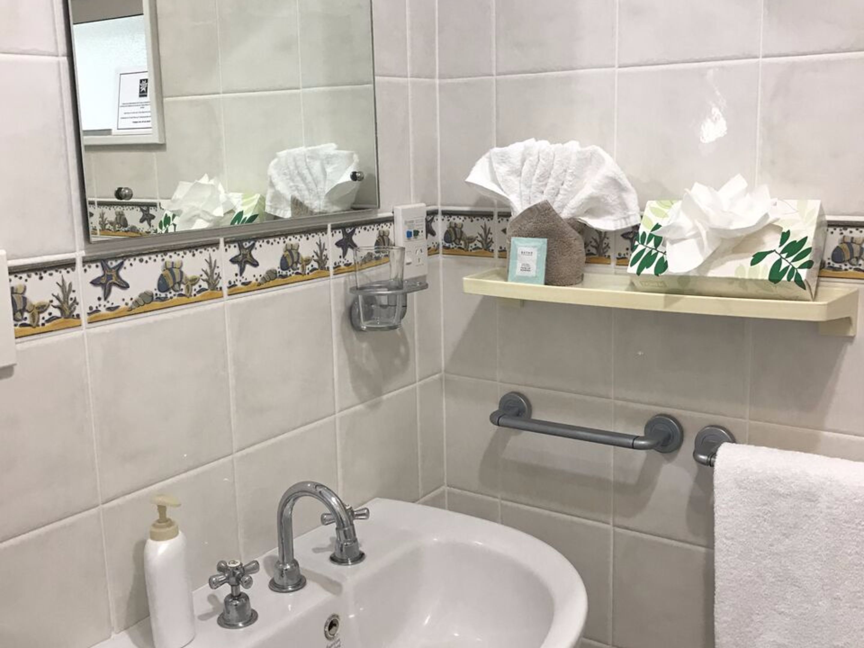 A bathroom with a sink, mirror, and towel rack.