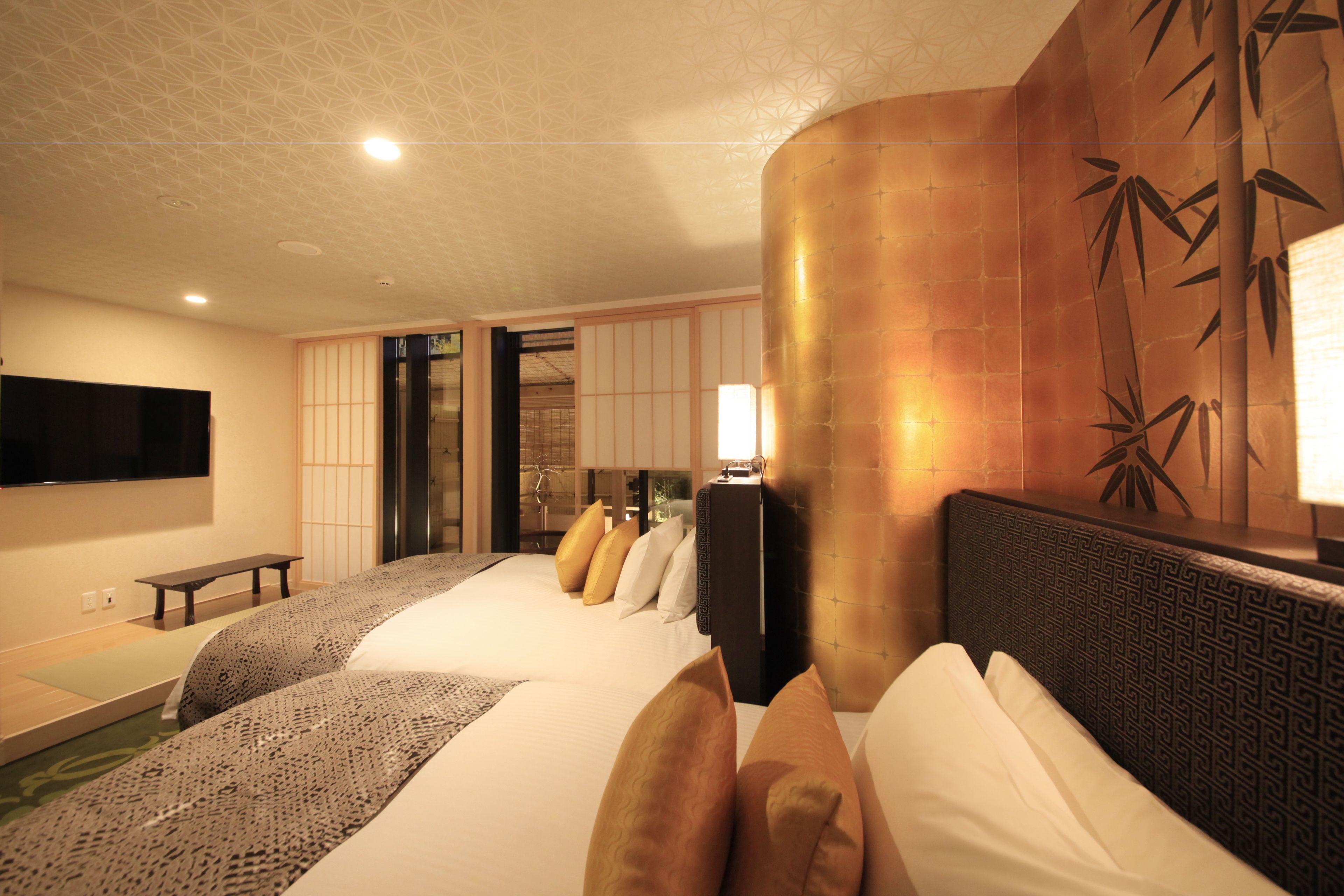 Habitación de hotel con una cama grande, una mesita de noche, un televisor de pantalla plana y un panel decorativo en la pared.
