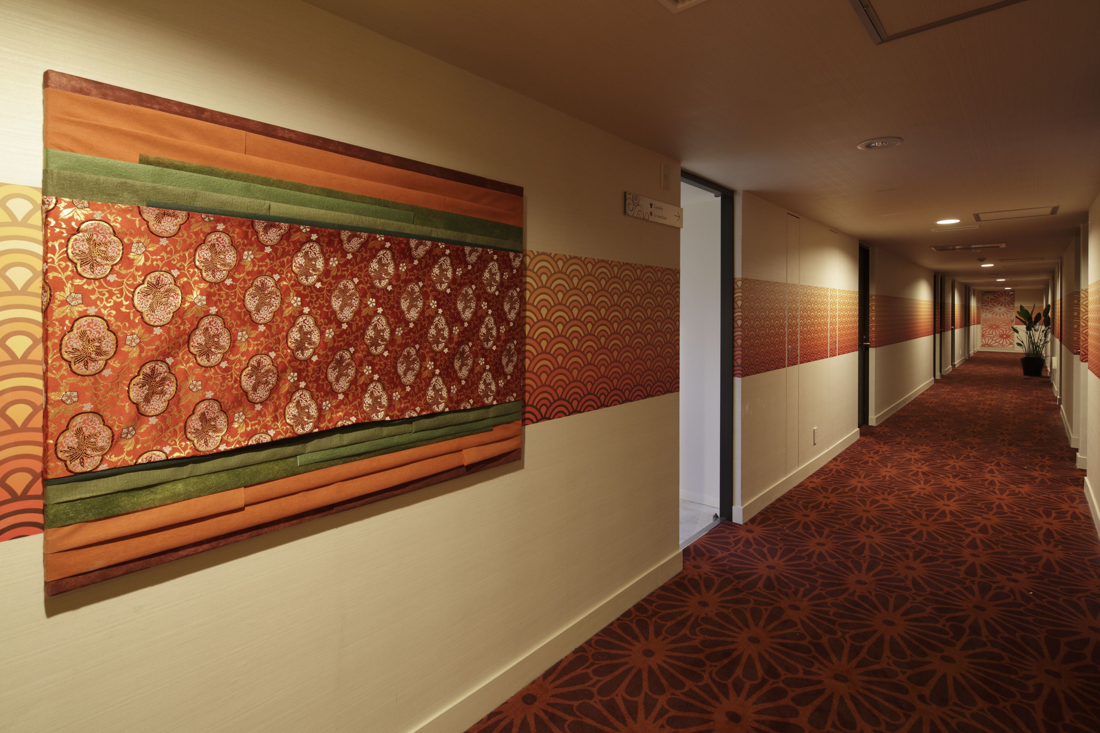 A hotel corridor with patterned wall panels and a carpeted floor.