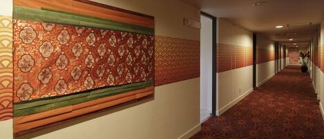A hotel corridor with patterned wall panels and a carpeted floor.