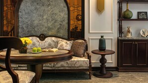 A cozy seating area with a sofa, a round table, and a decorative lamp. - Romantique Hotel De Hanoi (Hanoi)