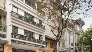 A hotel with a marble entrance, a staircase leading to the entrance, and a tree in front. - Romantique Hotel De Hanoi (Hanoi)