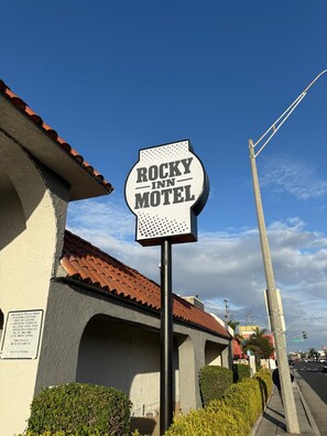 Une enseigne de motel portant le nom « ROCKY INN MOTEL » et un panneau d’avertissement concernant les véhicules non autorisés.