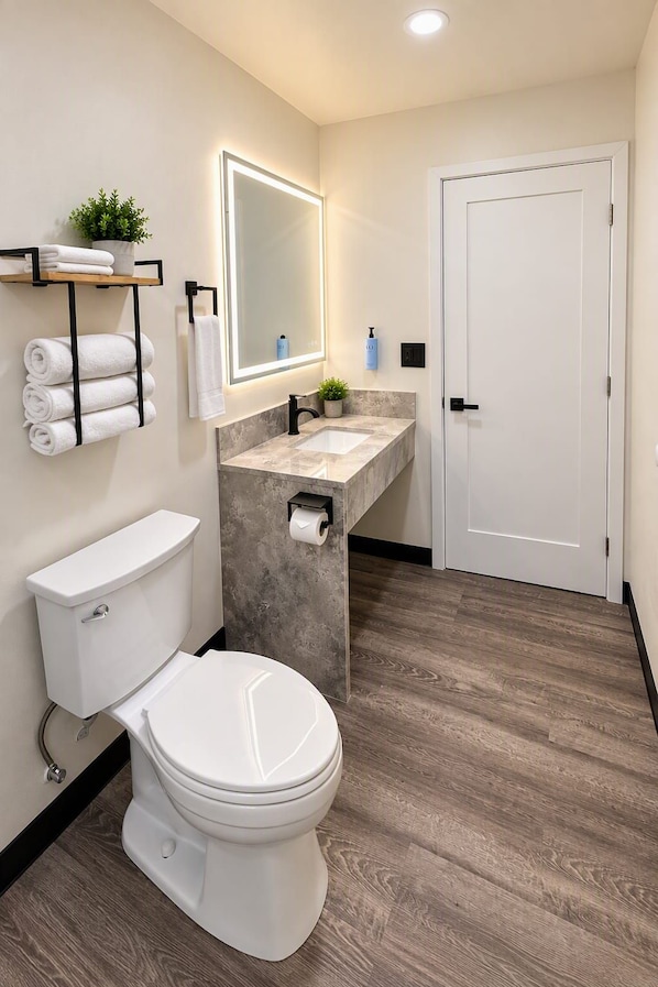 A modern bathroom with a toilet, sink, and mirror. - Rocky Inn Motel (Long Beach)